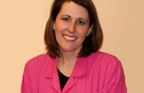 Woman in a pink uniform smiling at the camera.