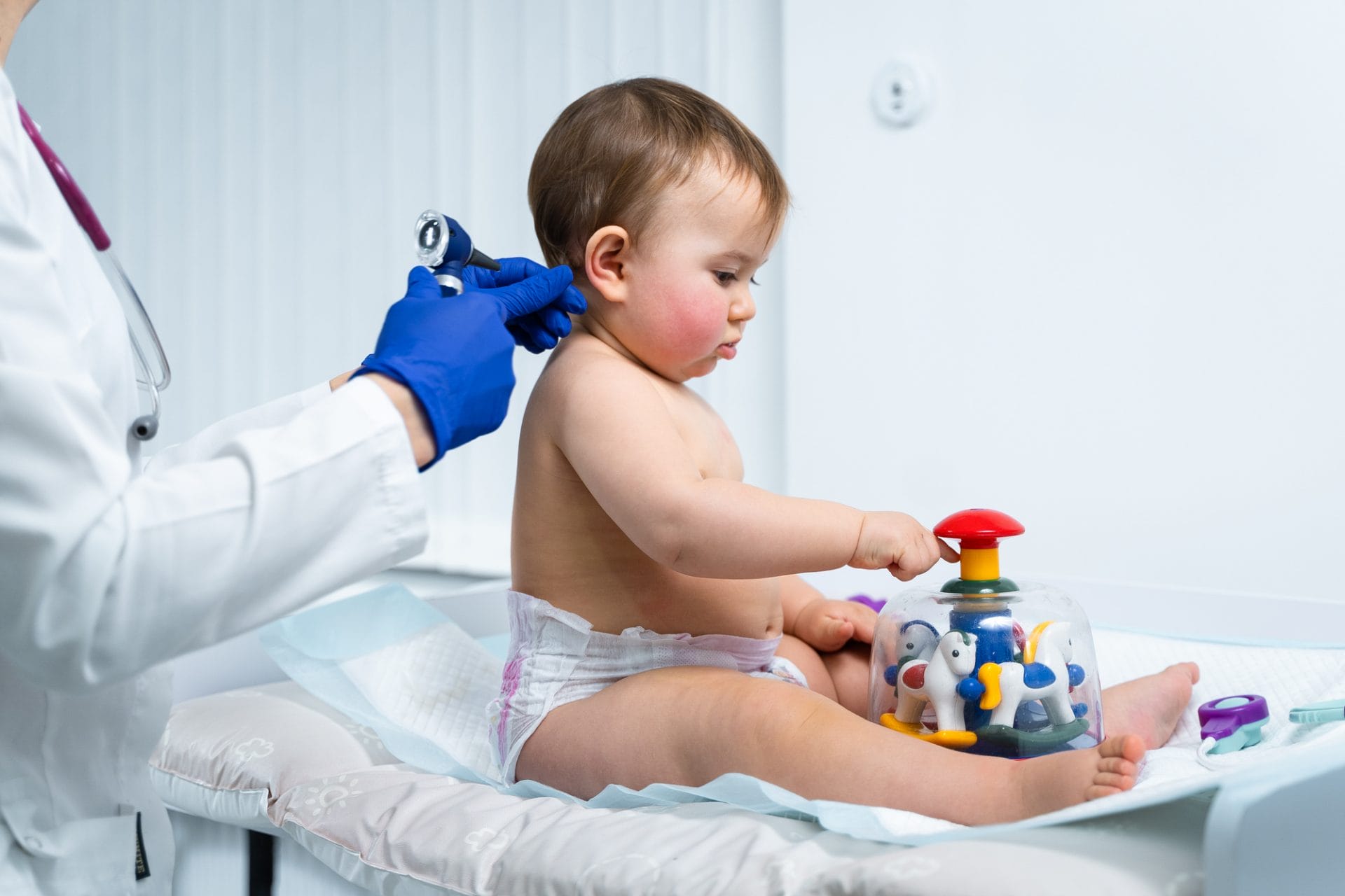Toddler being distracted with a toy during a medical examination.