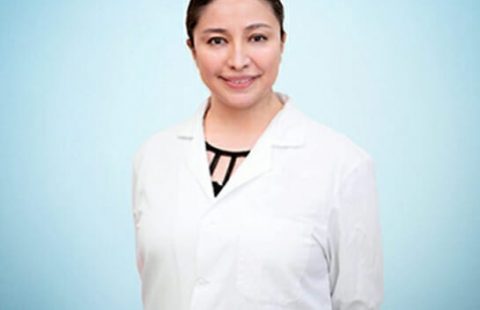 A confident healthcare professional wearing a white lab coat against a blue background.