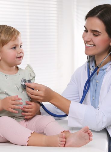 Pediatrician carrying out a checkup on a young child with a stethoscope.