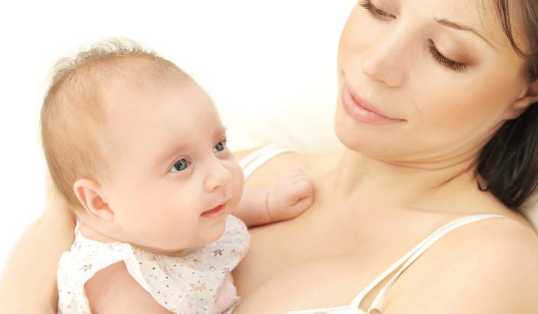 A woman gazes lovingly at the baby in her arms, who looks upwards with a curious expression. They are both bathed in soft, natural light. A woman gazes lovingly at the baby in her arms, who looks upwards with a curious expression. They are both bathed in soft, natural light.